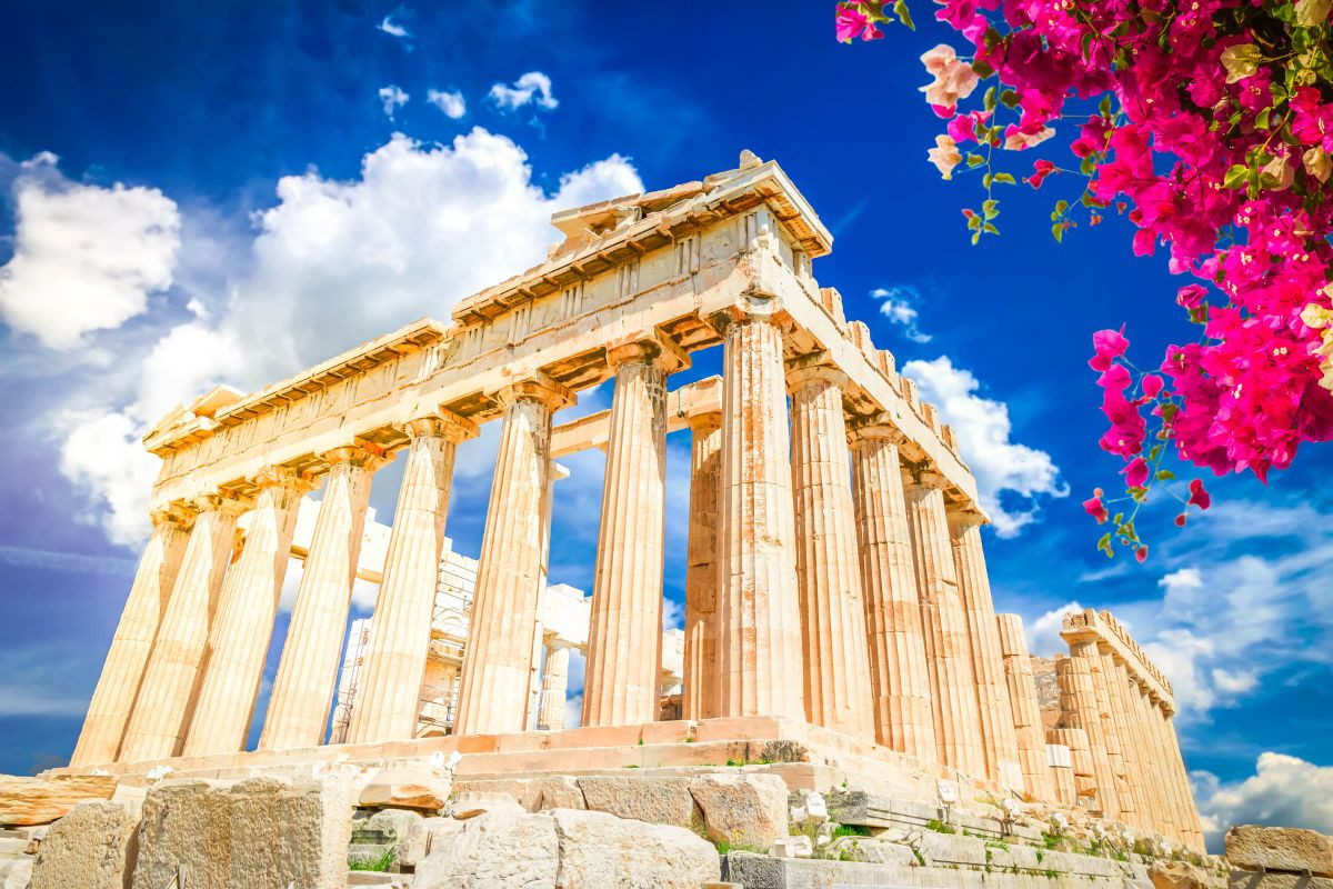 The Parthenon framed by blooming flowers under a blue sky.
